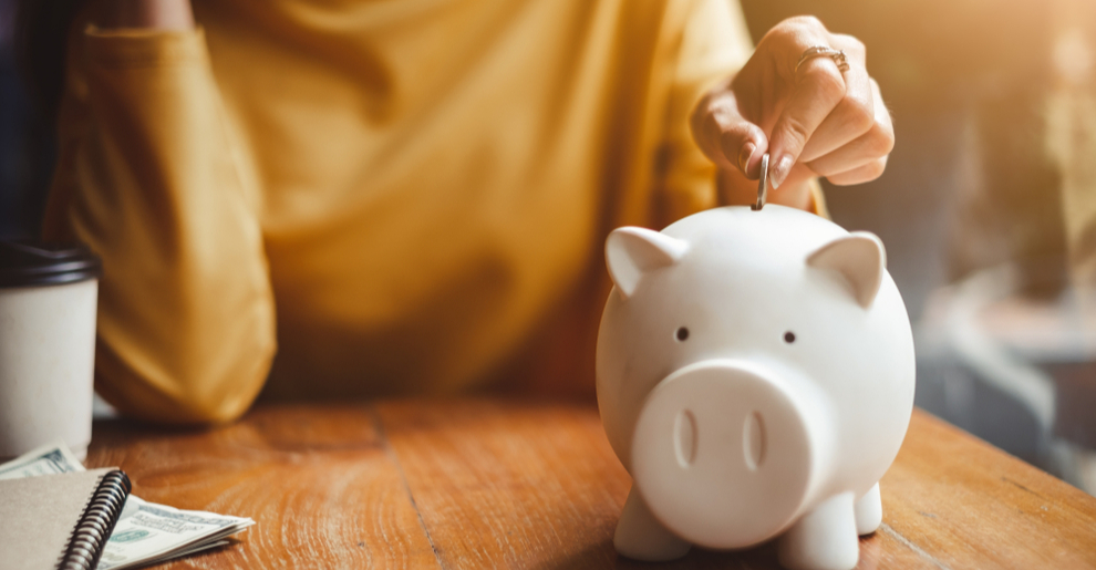 A woman depositing a coin into a piggy bank. 