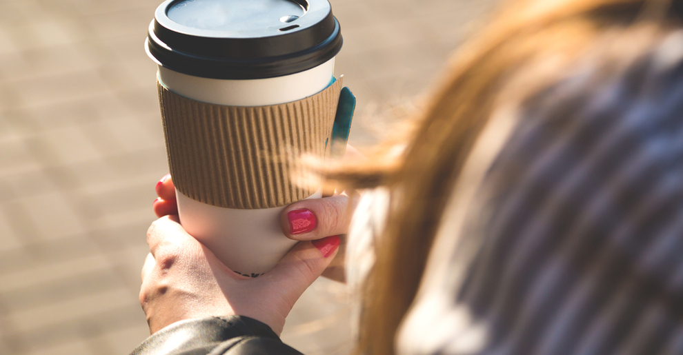 A woman holding a takeaway cup of coffee. 
